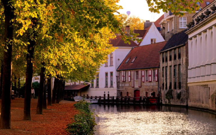 Historic canal in Germany lined with fall trees and colorful leaves on a calm evening