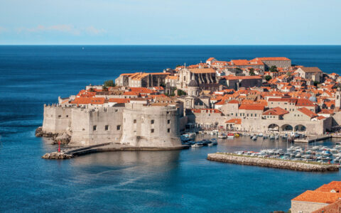 Aerial view of harbor of medieval walled city of Dubrovnik, Croatia with its terracotta roofs on a sunny day.