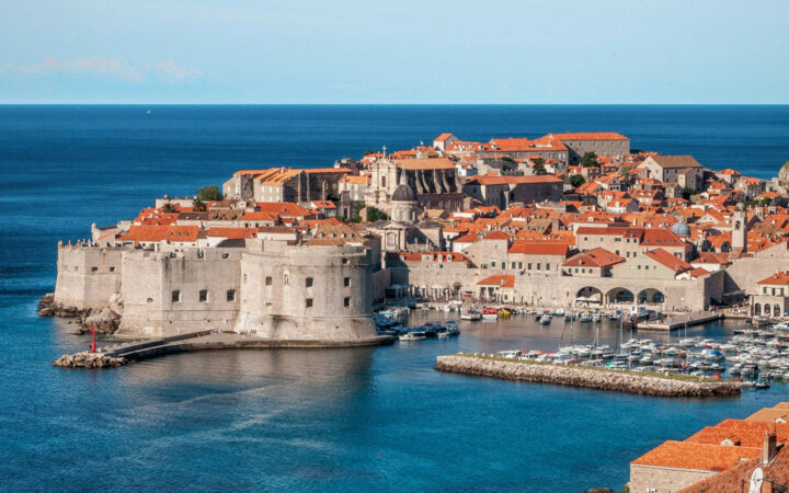 Aerial view of harbor of medieval walled city of Dubrovnik, Croatia with its terracotta roofs on a sunny day.