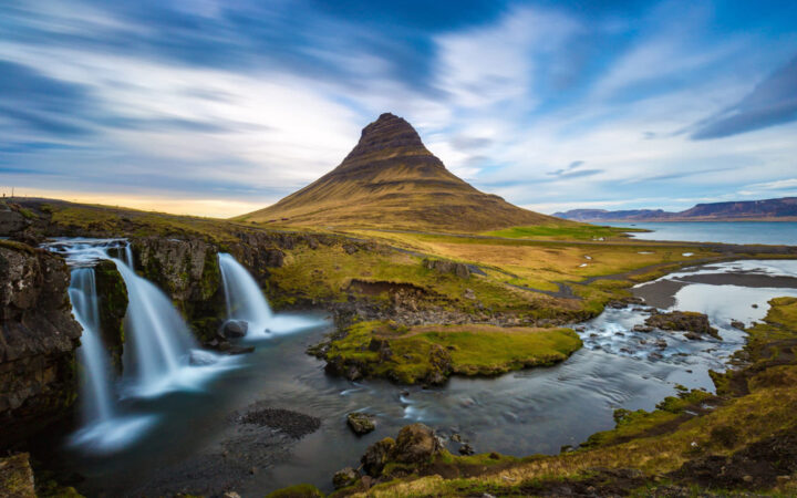 A trio of waterfalls at Kirkjufell Iceland seen by a river and pointed mountain