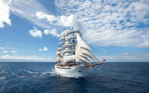 Sea Cloud II sailing off into the distance on a cloudy day with calm seas