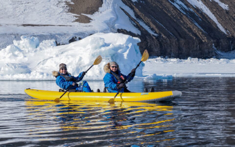 Kayakers in cold weather clothing explore the icy waters of svalbard- iceland-greenland