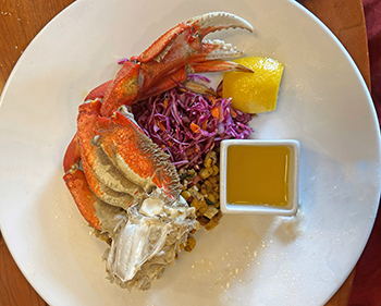 Alaskan king crab over a bed of corn and purple cabbage with butter and lemon on a white plate