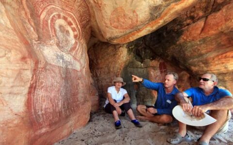 a guide points to indigenous cave art on a tour during the Kimberley - Cruising to the Australian Outback small ship cruise trip