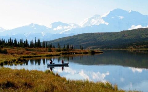 two people paddling canoe across lake on camp denali adventure