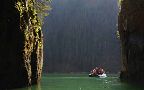 Zodic explring the narrow waterways of Alaska shown between 2 large landforms on a bright sunny day