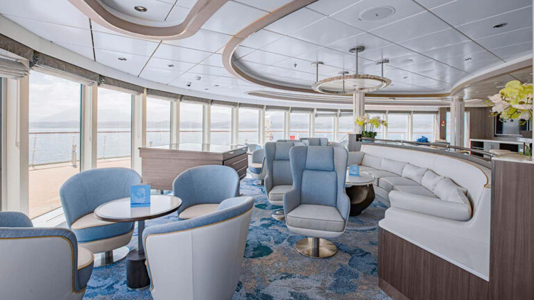 Observers lounge with comfortable white and blue seating and large windows aboard polar expedition ship Ocean Victory