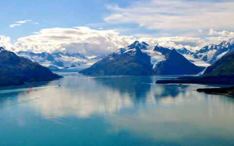 Areal view of Prince William Sound in Alaska, teal water surrounded by snow topped mountain range