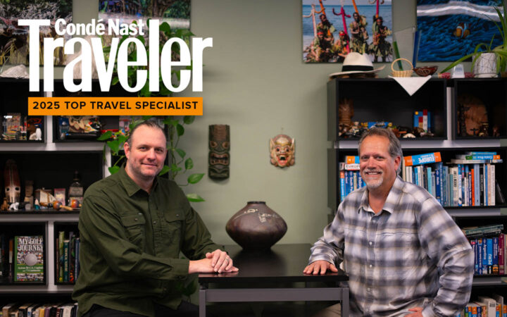 Travel specialists sitting at a table next to bookshelves stacked with books and items brought back from travels