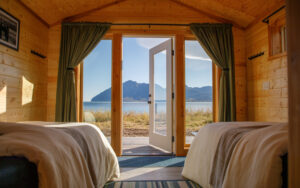 View looking out of the Bear Camp Alaska cabin with large windows and glass pain door