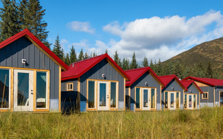 small camp with modern small personal lodges set amongst forest, river, open grassland & large mountains in Alaska.