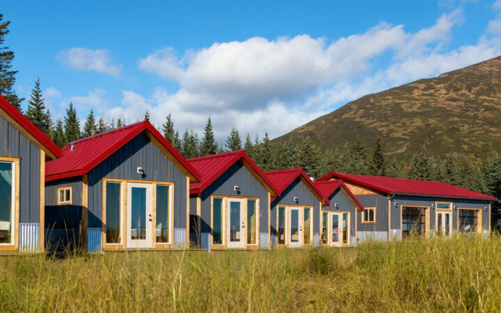 small camp with modern small personal lodges set amongst forest, river, open grassland & large mountains in Alaska.