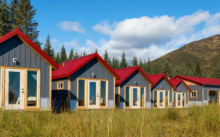 small camp with modern small personal lodges set amongst forest, river, open grassland & large mountains in Alaska.