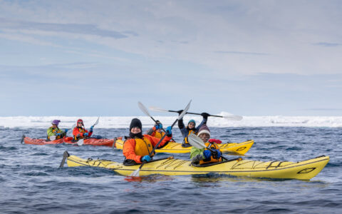 Travelers kayak beside sea ice during a Svalbard small ship cruise.