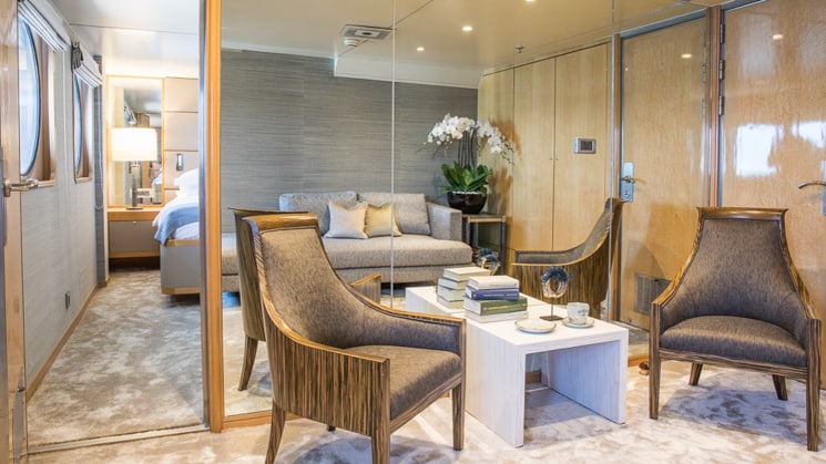 Seating area inside category 1 cabin aboard Indonesian yacht aqua blue, floor to ceiling mirrors and two arm chairs with side table
