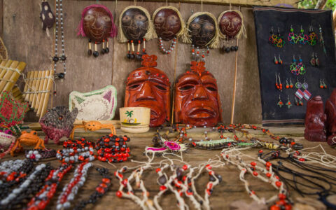 A collection of colorful indigenous Amazonian handicrafts is displayed for sale at a market stall.