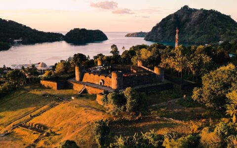 Fort Belgica glows during golden hour sunset towering on a small hill of Neira Island in Indonesia not far from the ocean.