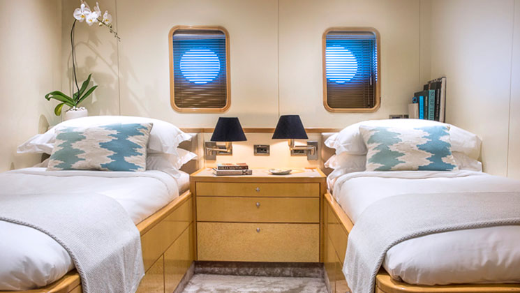 2 twin beds with vertical porthole windows, wooden accents & furniture in category 3 cabin board Indonesia yacht aqua blu