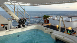 Jacuzzi & gym equipment on covered deck near white sun loungers aboard Aqua Blu Indonesia luxury yacht.