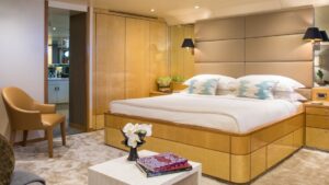 double bed against cushioned tan leather headboard wooden accents on the bed frame with tan carpet.