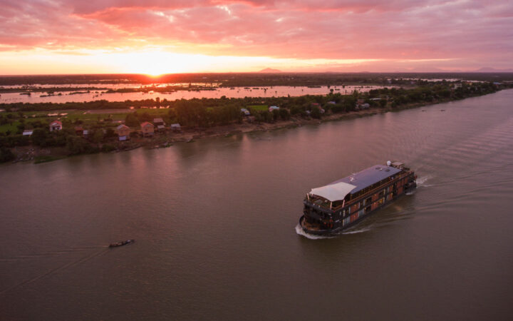 Aerial of river cruise ship Aqua Mekong cruising on Tonle Sap river at sunset, Kampong Tralach, Kampong Chhnang, Cambodia.
