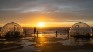 Deck 7, GeoDomes, aboard the ship Greg Mortimer with a traveler standing on deck looking out at the sunset