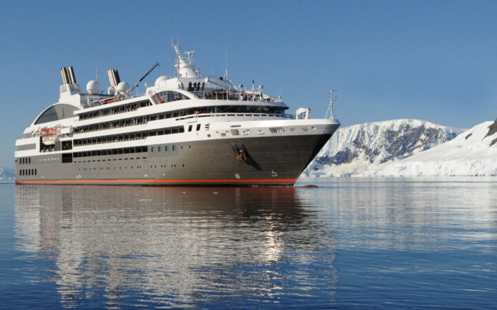 Exterior of expedition ship L'Austral with 6 passenger decks & gray hull, cruising in Antarctica.