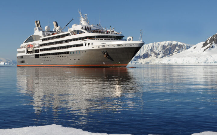 Exterior of expedition ship L'Austral with 6 passenger decks & gray hull, cruising in Antarctica.