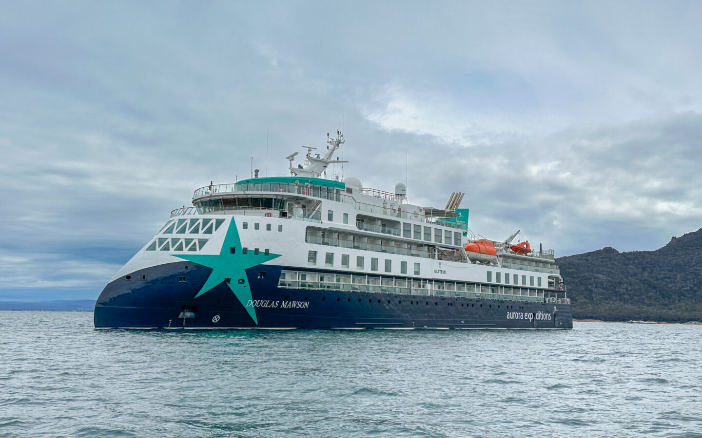 Exterior shot of Douglas Mawson anchored in a bay off the coast of Australia on a cloudy day with calm seas