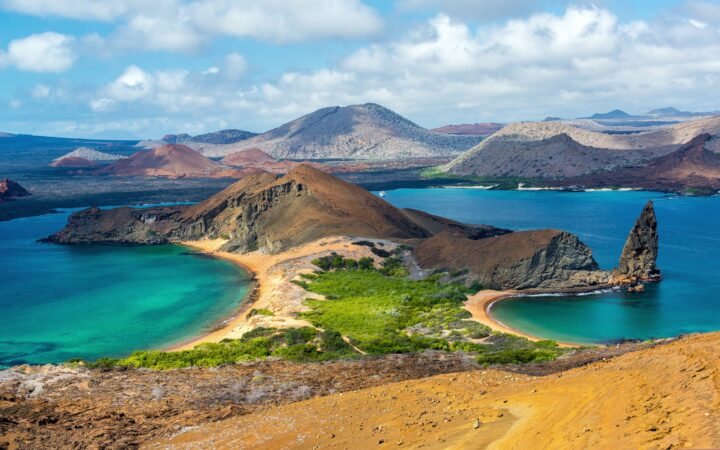 Overview of Bartolome Island in the Galapagos Islands showing Pinnacle Rock and other hills, cliffs and beaches.