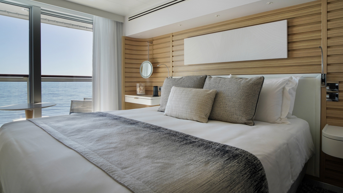 Prestige Stateroom - Decks 4, 5 & 6 aboard French expedition ship Le Bellot, with king bed, white linens, chic decor & private balcony.