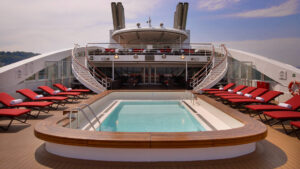 Deck 6 aboard Le Boreal red lounge chairs line the outside of a heated outdoor pool