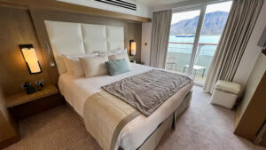 owners suite aboard Le Boreal luxury expedition ship, white leather headboard and a seating area
