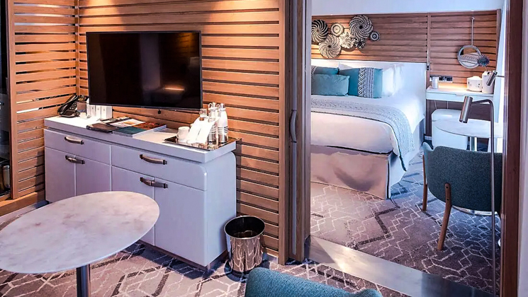 2-room Prestige Suite aboard Le Champlain French small ship, with ethnic chic decor, white linen king bed, private balcony, wooden walls, desk & chair.