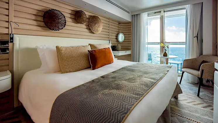 Prestige Stateroom - Decks 4, 5 & 6 aboard French expedition ship Le Dumont D'Urville, with king bed, white linens, chic ethnic decor & private balcony.