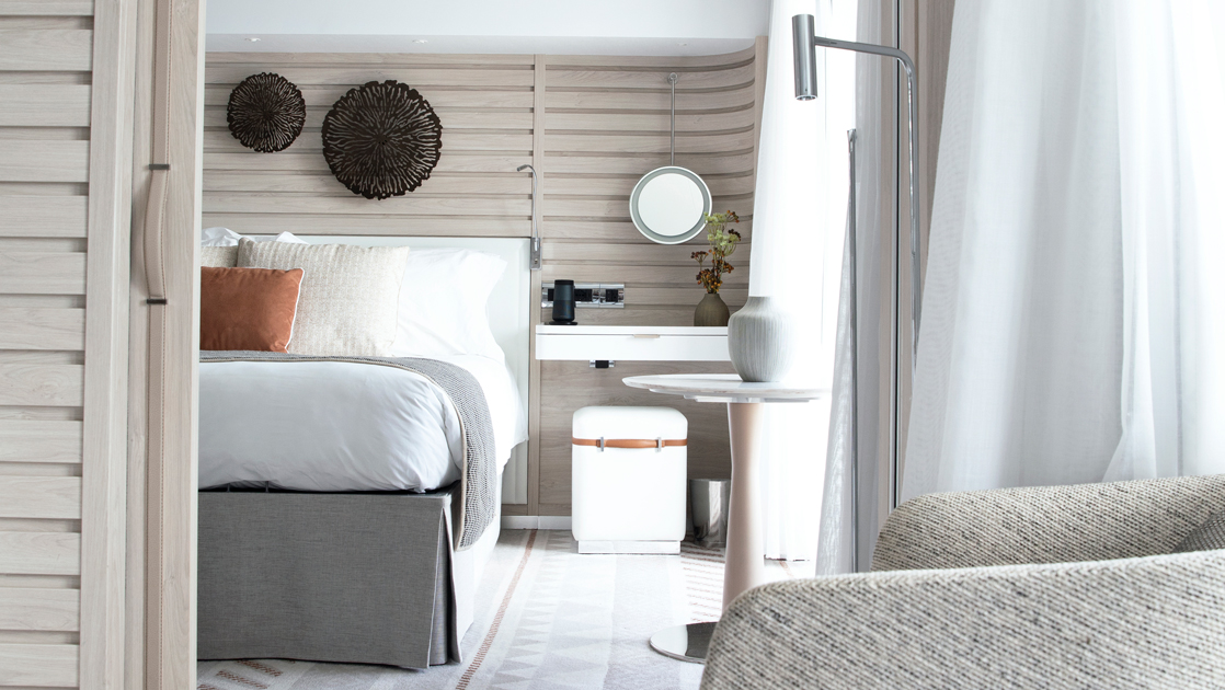 2-room Prestige Suite aboard Le Dumont D'Urville french small ship, with ethnic chic decor, white linen king bed, private balcony, wooden walls, desk & chair.