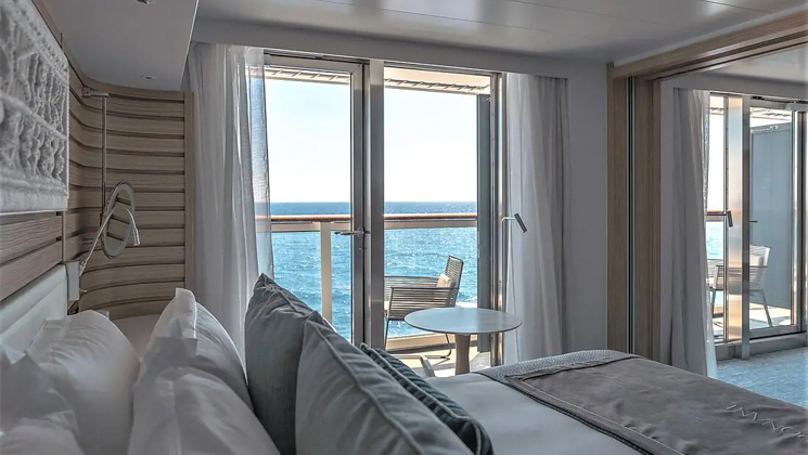 Prestige Suite aboard Le Jacques Cartier French small ship, with ethnic chic decor, white linen king bed, private balcony & wooden walls.