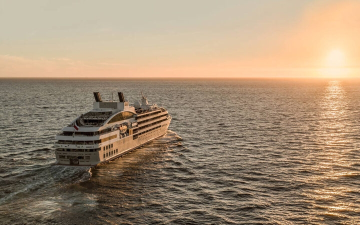 Luxury French ship Le Lyrial cruises toward the sunset, out at sea.