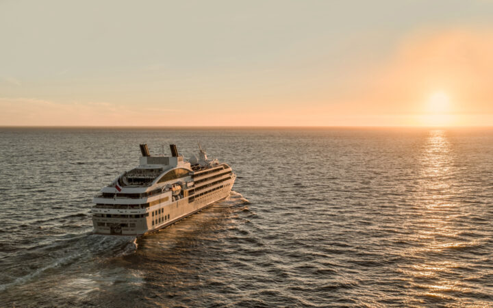 Luxury French ship Le Lyrial cruises toward the sunset, out at sea.