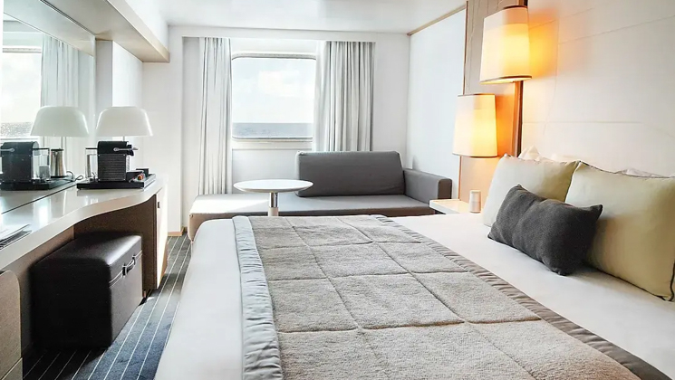 Superior Stateroom with king bed aboard Le Soleal luxury expedition ship, beige walls, white bedding & headboard & brown accent pillows