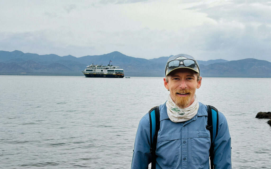 portrait of travel expert Kevin Marshall in Baja with the Lindblad National Geographic Venture behind him