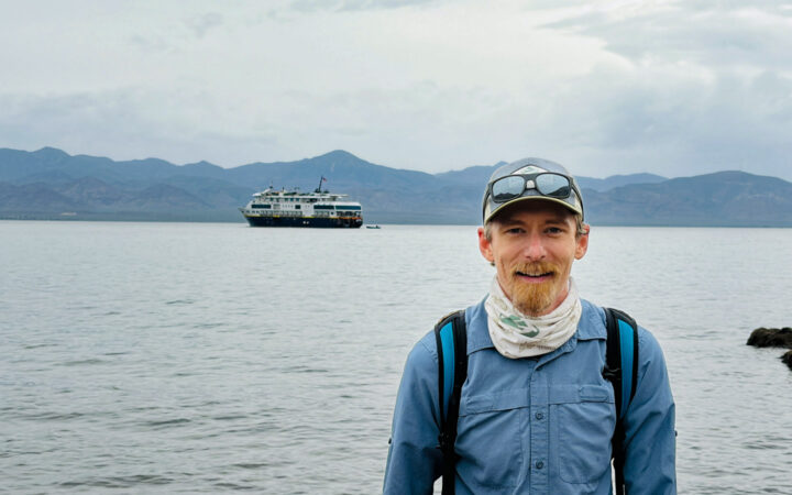 portrait of travel expert Kevin Marshall in Baja with the Lindblad National Geographic Venture behind him