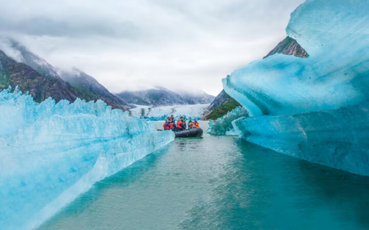Zodiac cruises through the deep blue waters of Alaska's Endicott Arm Fjord towards the majestic Dawes Glacier