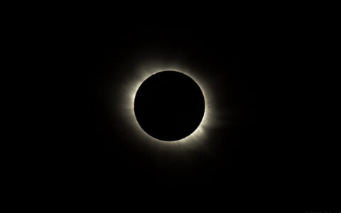 Total solar eclipse with black sky & black moon ringed with small amount of golden light.