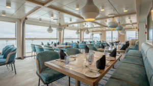Dining area aboard small ship cruise with floor to ceilings windows and views of antarctica