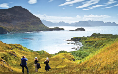 Lindblad Expeditions guests in Antarctica, South Georgia, and the Falklands hiking through the grassy hills overlooking the beautiful waterways