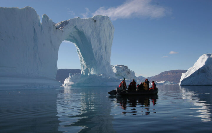 A zodiac cruises through the waters off Spitsbergen northeast Greenland surrounded by ice which forms an arch formation