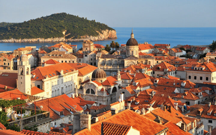 Aerial view of Dubrovnik, Croatia with its red-tiled roofs, stone buildinga, domes & seaside setting.