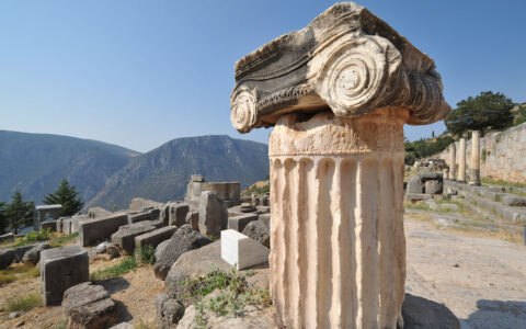 Tan ancient Grecian column sits near other ruins on a hilltop in the sunshine on a Le Ponant Cyclades small ship cruise.
