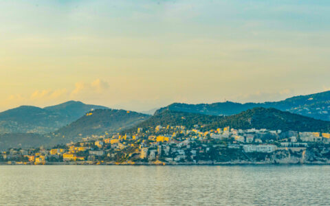 Nice, France at sunset with hillside buildings backed by green mountains, seen on a small ship cruise in the French Riviera.